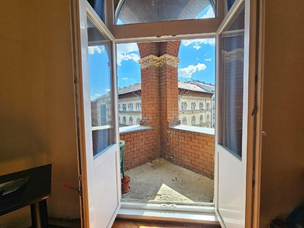 Erkély téglafallal és erkélyajtóval, kilátással a városra